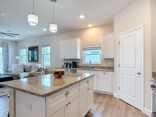 3121 Portofino Blvd, New Smyrna Beach, FL 32168 - kitchen featuring healthy amount of natural light, light wood-type flooring, a kitchen island, white cabinets, and recessed lighting