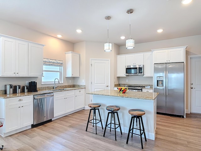 3121 Portofino Blvd, New Smyrna Beach, FL 32168 - kitchen with appliances with stainless steel finishes, white cabinetry, light wood-type flooring, a breakfast bar area, and recessed lighting