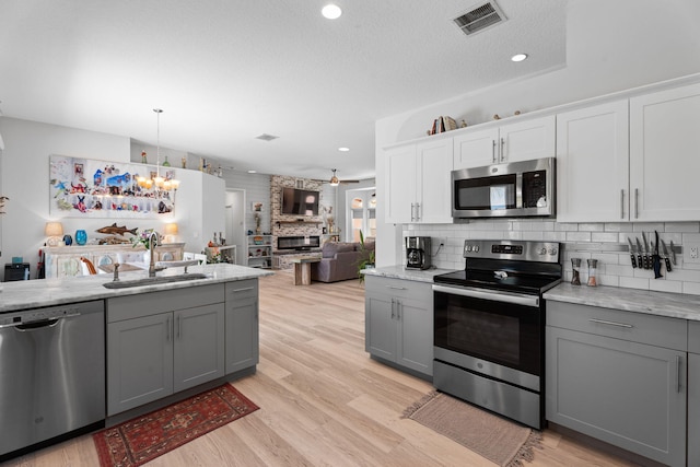 2051 SW Pruitt St, Port Saint Lucie, FL 34953 - kitchen featuring appliances with stainless steel finishes, gray cabinets, a chandelier, decorative backsplash, and light wood-type flooring
