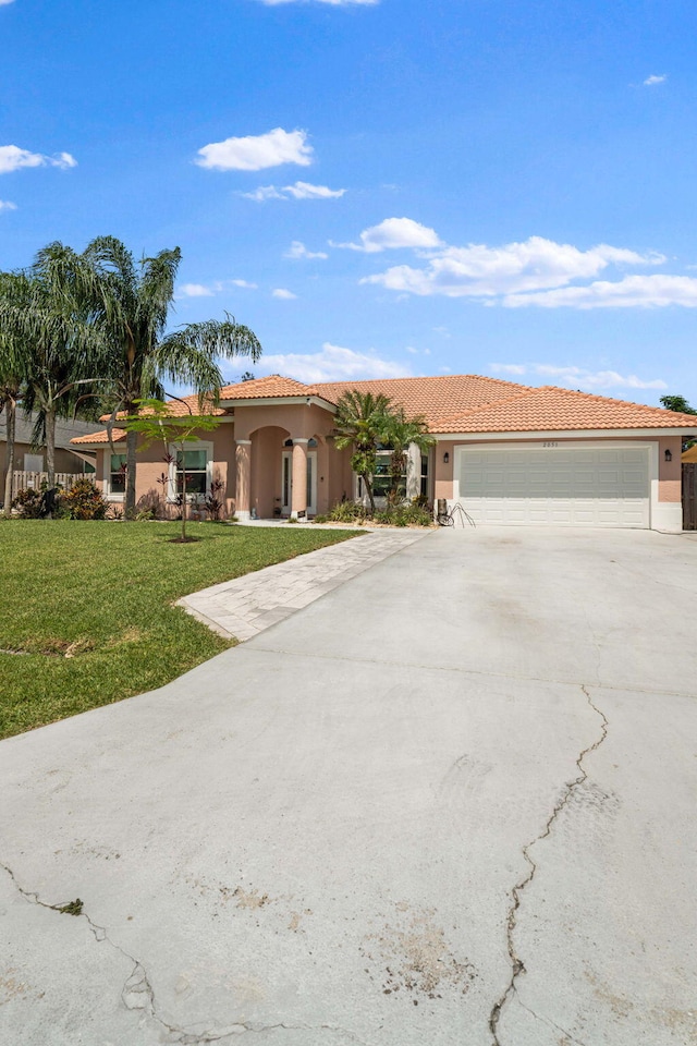 2051 SW Pruitt St, Port Saint Lucie, FL 34953 - mediterranean / spanish-style home featuring stucco siding, concrete driveway, a garage, a front yard, and a tile roof