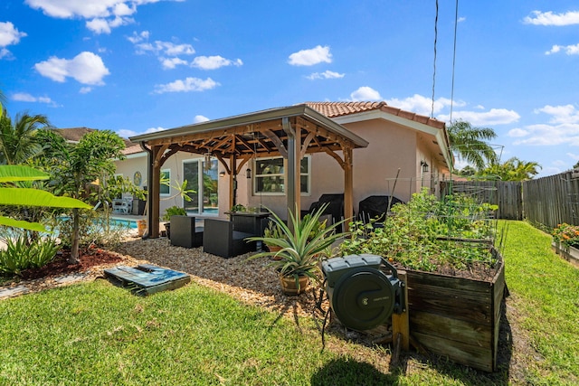 2051 SW Pruitt St, Port Saint Lucie, FL 34953 - back of property with a gazebo, a vegetable garden, stucco siding, and a tiled roof