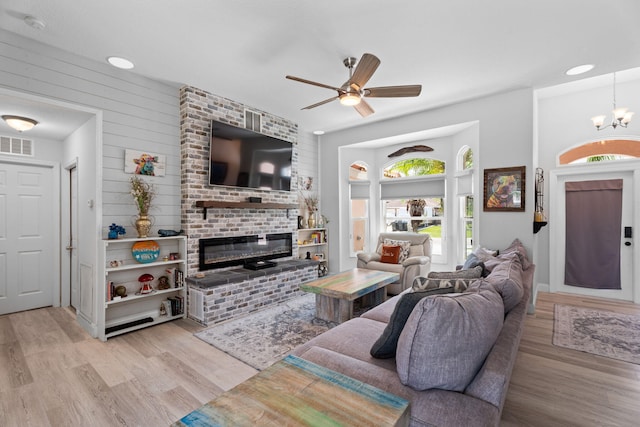 2051 SW Pruitt St, Port Saint Lucie, FL 34953 - living room featuring light wood-style floors, a fireplace, ceiling fan, and a chandelier