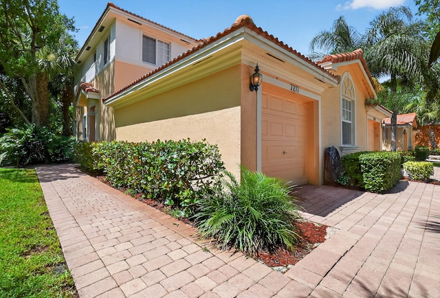 7271 Briella Dr, Boynton Beach, FL 33437 - view of property exterior with an attached garage, stucco siding, a tiled roof, and driveway