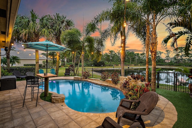 6126 SE Split Oak Trl, Hobe Sound, FL 33455 - pool at dusk featuring a patio area, a fenced backyard, and a water view