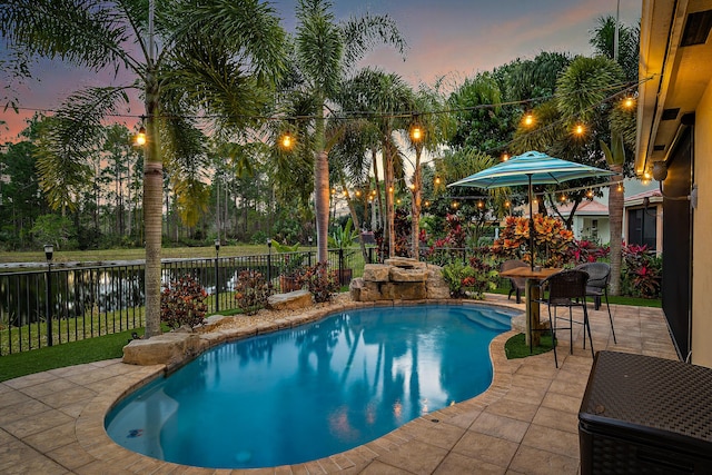 6126 SE Split Oak Trl, Hobe Sound, FL 33455 - pool at dusk with a patio, a fenced backyard, and a water view