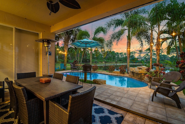 6126 SE Split Oak Trl, Hobe Sound, FL 33455 - pool at dusk featuring a patio area, a ceiling fan, a fenced backyard, and outdoor dining space
