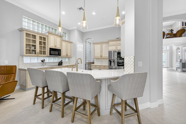 8168 Valhalla Dr, Delray Beach, FL 33446 - kitchen with stainless steel fridge, black microwave, arched walkways, cream cabinets, and crown molding