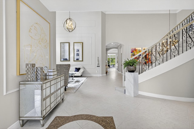 8168 Valhalla Dr, Delray Beach, FL 33446 - entryway with arched walkways, a chandelier, stairs, tile patterned flooring, and a towering ceiling