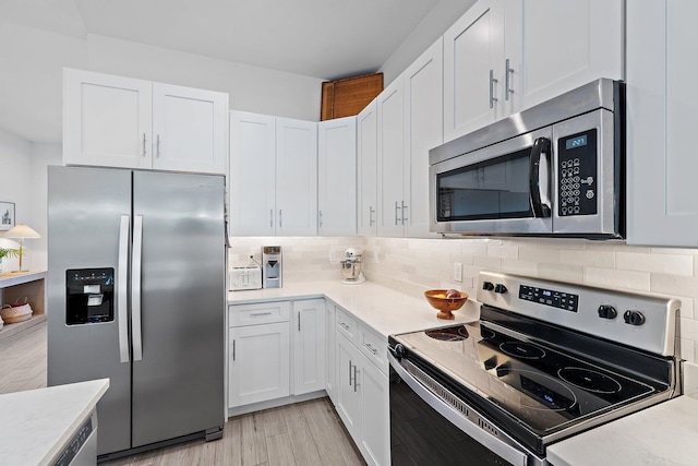 17742 Evangeline Ave, Jupiter, FL 33458 - kitchen featuring appliances with stainless steel finishes, white cabinetry, decorative backsplash, and light wood-style floors