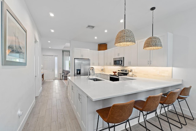 17742 Evangeline Ave, Jupiter, FL 33458 - kitchen with stainless steel appliances, tasteful backsplash, white cabinetry, a kitchen breakfast bar, and recessed lighting