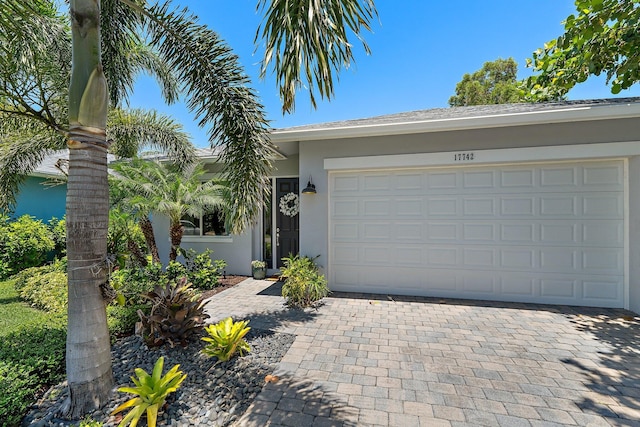 17742 Evangeline Ave, Jupiter, FL 33458 - ranch-style home with stucco siding, decorative driveway, and an attached garage