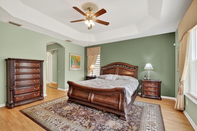 11291 Barca Blvd, Boynton Beach, FL 33437 - bedroom featuring a tray ceiling, arched walkways, multiple windows, and light wood-style flooring