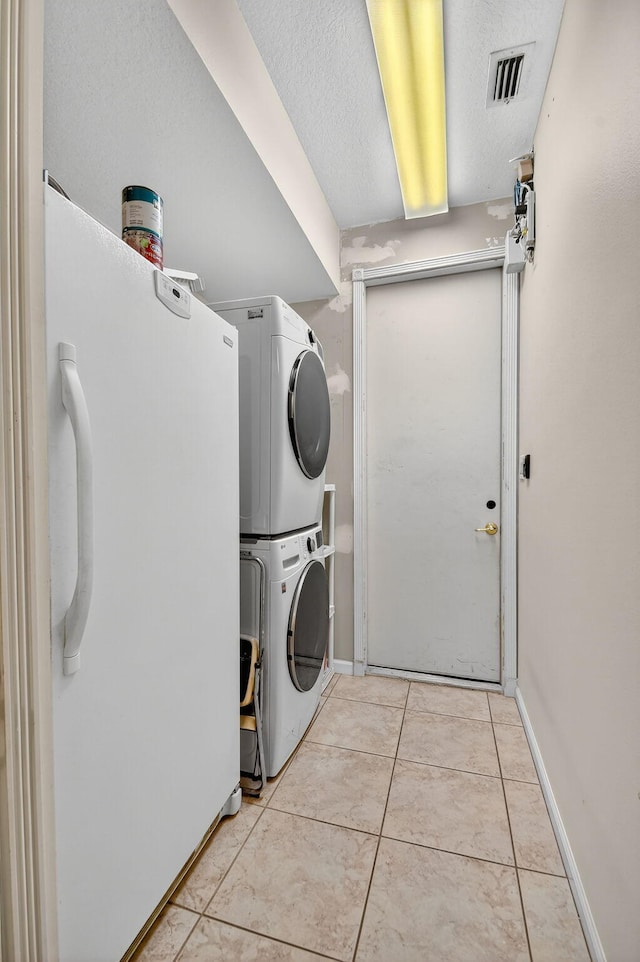 11291 Barca Blvd, Boynton Beach, FL 33437 - laundry area featuring stacked washing machine and dryer, tile patterned floors, and a textured ceiling