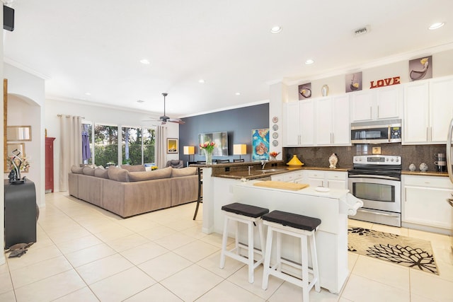 63 Lake Eden Dr, Boynton Beach, FL 33435 - kitchen featuring appliances with stainless steel finishes, crown molding, a peninsula, recessed lighting, and decorative backsplash