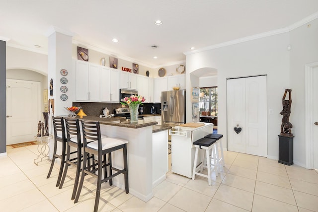 63 Lake Eden Dr, Boynton Beach, FL 33435 - kitchen with appliances with stainless steel finishes, crown molding, a peninsula, light tile patterned floors, and arched walkways