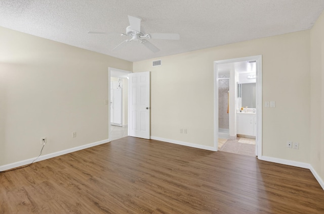 9521 Boca Cove Cir Unit 508, Boca Raton, FL 33428 - unfurnished bedroom featuring wood finished floors, connected bathroom, a textured ceiling, and ceiling fan