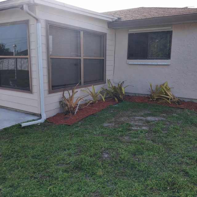 2482 SE Floresta Dr, Port Saint Lucie, FL 34984 - view of property exterior with a shingled roof, a lawn, and stucco siding