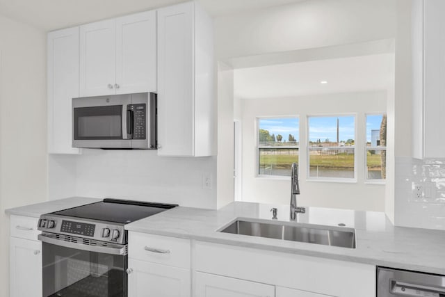 400 Riverside Dr, Palm Beach Gardens, FL 33410 - kitchen with stainless steel appliances, white cabinetry, decorative backsplash, and light stone counters