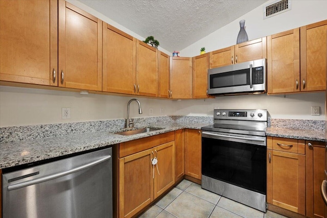 6015 Raintree Trl, Fort Pierce, FL 34982 - kitchen with appliances with stainless steel finishes, a textured ceiling, light tile patterned floors, lofted ceiling, and light stone counters