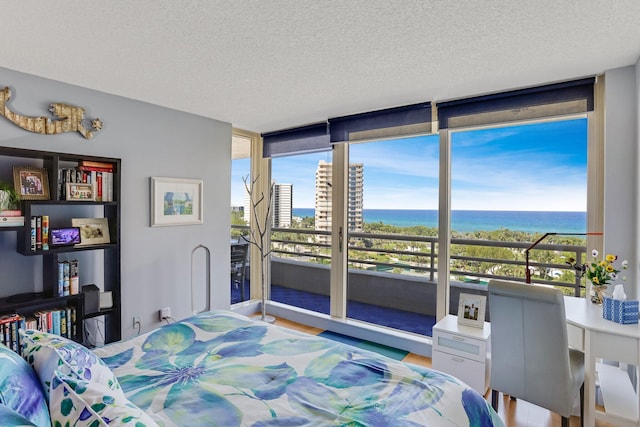 4101 N Ocean Blvd Unit 908, Boca Raton, FL 33431 - bedroom with a textured ceiling, a water view, expansive windows, and wood finished floors
