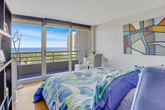 4101 N Ocean Blvd Unit 908, Boca Raton, FL 33431 - bedroom featuring a water view, a textured ceiling, a wall of windows, and wood finished floors