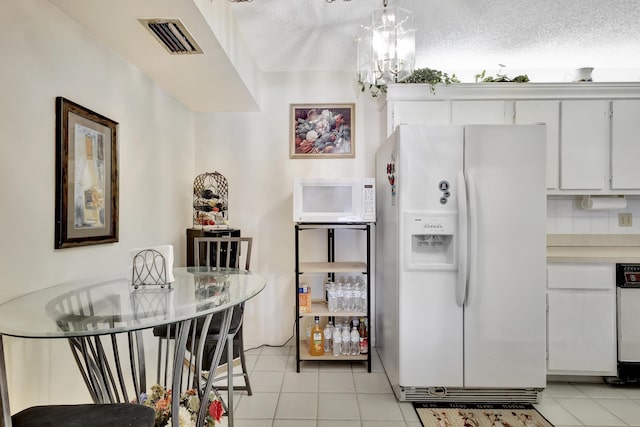 1102 Green Pine Blvd Unit A1, West Palm Beach, FL 33409 - kitchen featuring white appliances, light tile patterned floors, light countertops, white cabinets, and a textured ceiling