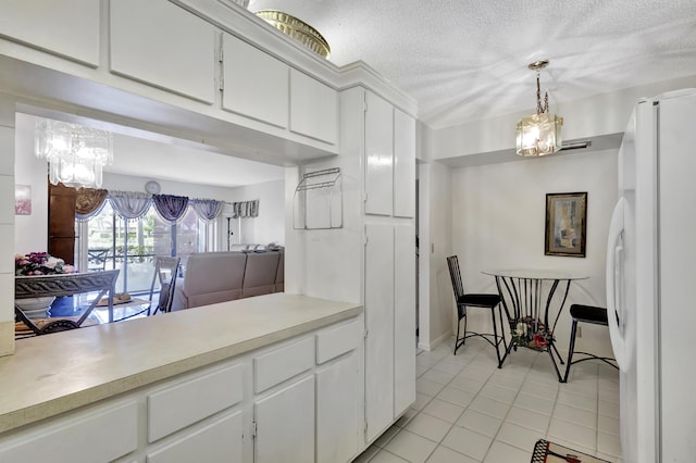 1102 Green Pine Blvd Unit A1, West Palm Beach, FL 33409 - kitchen featuring freestanding refrigerator, a chandelier, light countertops, light tile patterned floors, and a textured ceiling