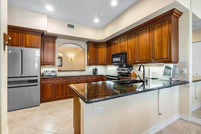 112 Palm Bay Dr Unit A, Palm Beach Gardens, FL 33418 - kitchen with stainless steel appliances, a peninsula, dark stone counters, light tile patterned floors, and tasteful backsplash