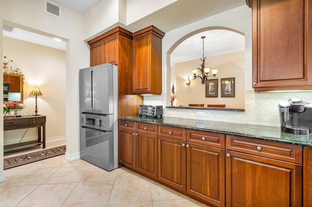 112 Palm Bay Dr Unit A, Palm Beach Gardens, FL 33418 - kitchen featuring freestanding refrigerator, arched walkways, a chandelier, backsplash, and brown cabinetry