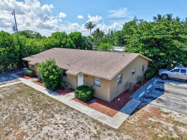 7891 Loomis St Unit 7891/7893, Lake Worth, FL 33462 - view of front of property with stucco siding, a shingled roof, uncovered parking, and view of scattered trees
