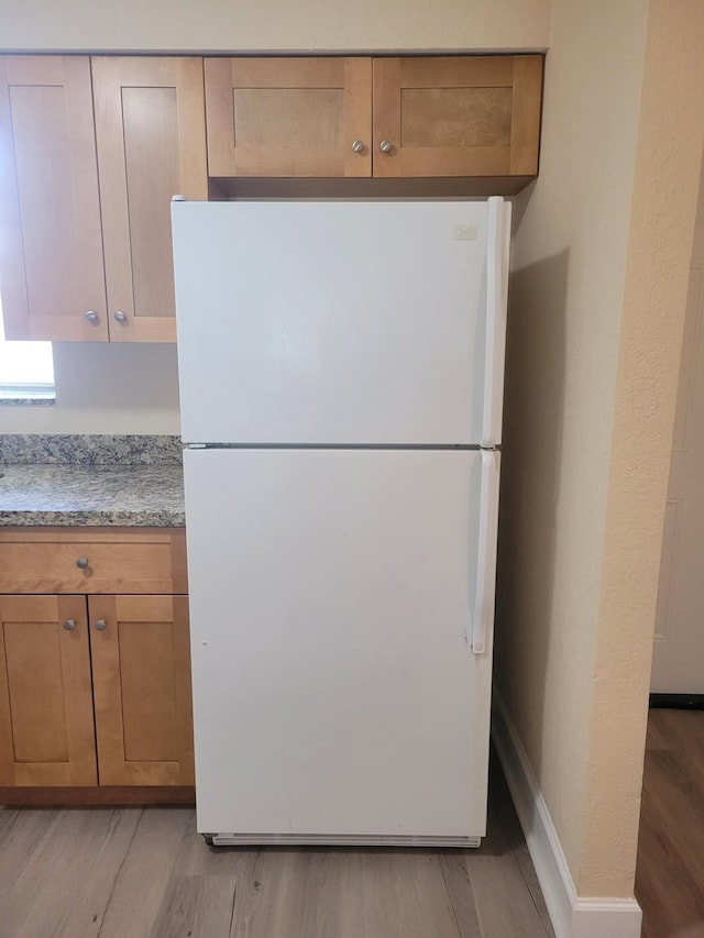 7891 Loomis St Unit 7891/7893, Lake Worth, FL 33462 - kitchen featuring freestanding refrigerator, light wood-style floors, light stone counters, and brown cabinets