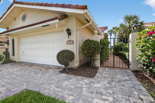 574 Emerald Way E, Deerfield Beach, FL 33442 - view of property exterior with a gate, stucco siding, decorative driveway, and a garage