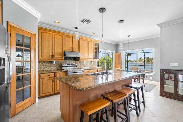 7141 Charleston Point Dr, Lake Worth, FL 33467 - kitchen with appliances with stainless steel finishes, under cabinet range hood, a breakfast bar, tasteful backsplash, and brown cabinetry