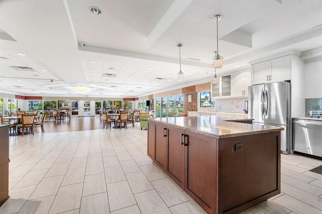 3310 S Ocean Blvd Unit 928D, Highland Beach, FL 33487 - kitchen featuring stainless steel appliances, a tray ceiling, a center island, light stone countertops, and glass insert cabinets