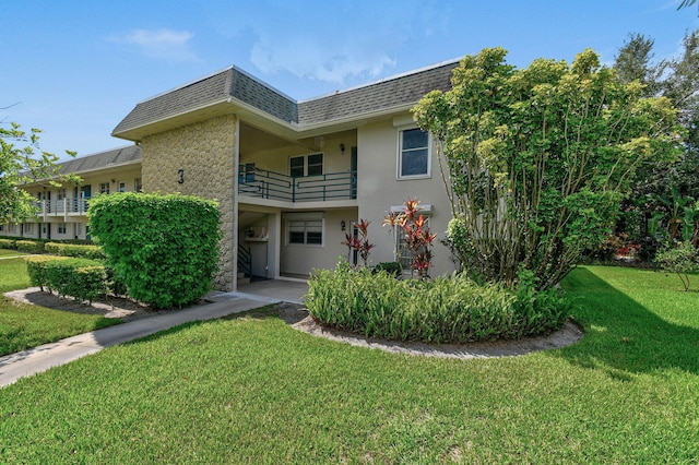 1900 S Kanner Hwy Unit 3-108, Stuart, FL 34994 - view of front of property featuring mansard roof, roof with shingles, stucco siding, and a front lawn