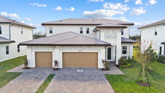 12240 SW 44th Ct, Davie, FL 33330 - view of front of house with a garage, decorative driveway, stucco siding, stone siding, and a front yard