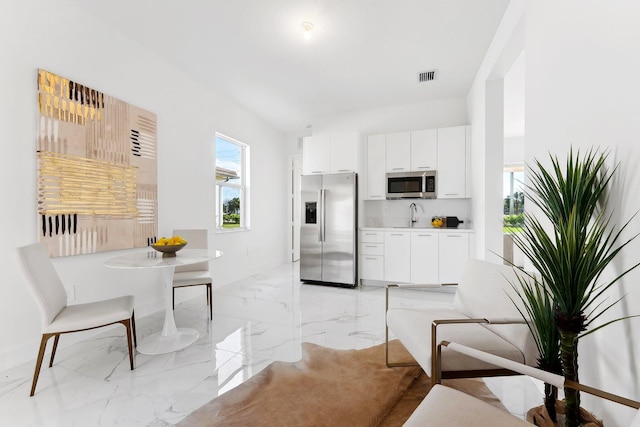 12240 SW 44th Ct, Davie, FL 33330 - kitchen with stainless steel appliances, light marble finish flooring, white cabinets, and light countertops