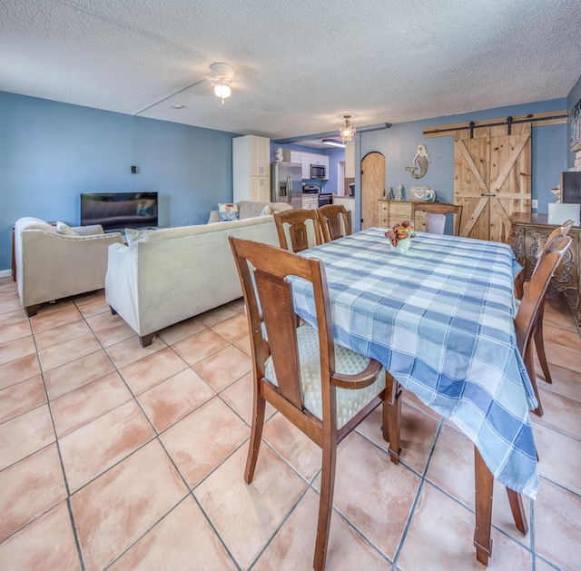 624 10th Ave N, Lake Worth Beach, FL 33460 - dining space featuring a ceiling fan, a barn door, a textured ceiling, and light tile patterned floors