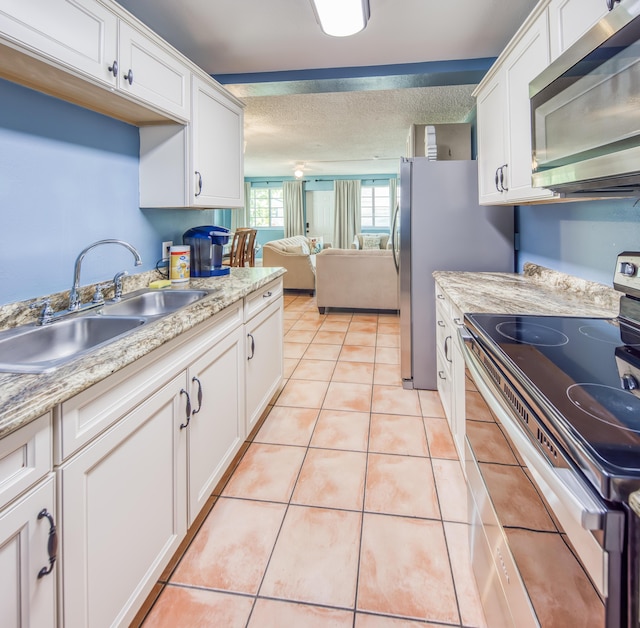 624 10th Ave N, Lake Worth Beach, FL 33460 - kitchen with appliances with stainless steel finishes, white cabinetry, light countertops, light tile patterned floors, and open floor plan