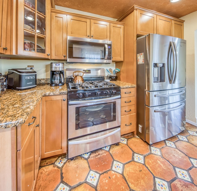 624 10th Ave N, Lake Worth Beach, FL 33460 - kitchen featuring appliances with stainless steel finishes, light stone counters, glass insert cabinets, and brown cabinets