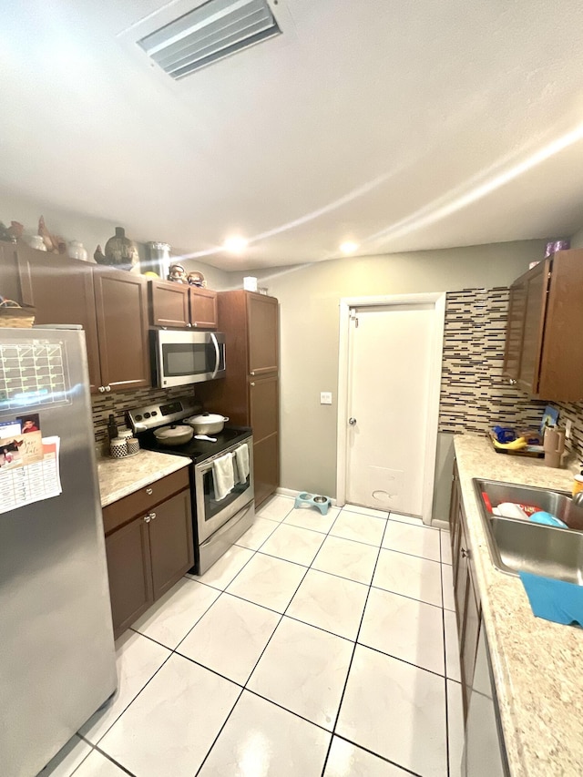 409 NE Oleander Ave, Port Saint Lucie, FL 34952 - kitchen featuring appliances with stainless steel finishes, tasteful backsplash, light countertops, and light tile patterned floors