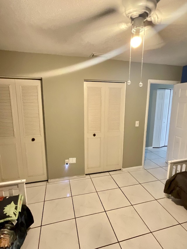409 NE Oleander Ave, Port Saint Lucie, FL 34952 - unfurnished bedroom with light tile patterned floors, ceiling fan, and a textured ceiling