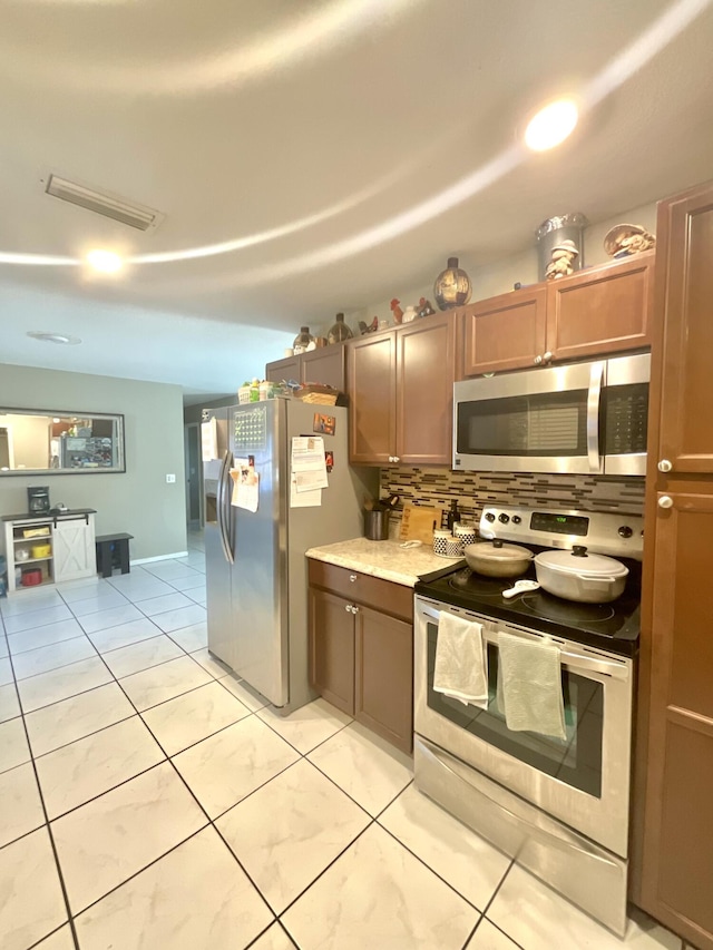 409 NE Oleander Ave, Port Saint Lucie, FL 34952 - kitchen with appliances with stainless steel finishes, tasteful backsplash, light countertops, and light tile patterned floors