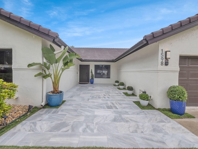 1598 SW 19th St, Boca Raton, FL 33486 - view of exterior entry featuring a tile roof, stucco siding, and a patio area