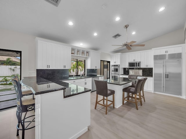 1598 SW 19th St, Boca Raton, FL 33486 - kitchen with stainless steel appliances, a kitchen bar, decorative backsplash, white cabinets, and a peninsula