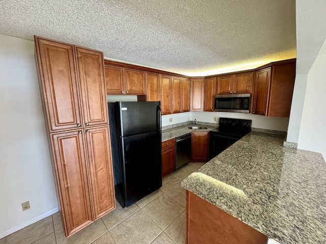 1119 Green Pine Blvd Unit C1, West Palm Beach, FL 33409 - kitchen with black appliances, brown cabinetry, a textured ceiling, light tile patterned flooring, and stone countertops