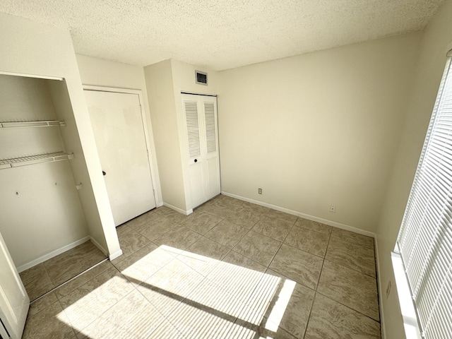1119 Green Pine Blvd Unit C1, West Palm Beach, FL 33409 - unfurnished bedroom with tile patterned flooring, a textured ceiling, and a closet