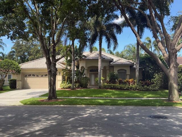 1133 Egret Cir S, Jupiter, FL 33458 - mediterranean / spanish home featuring an attached garage, stucco siding, driveway, a tiled roof, and a front yard