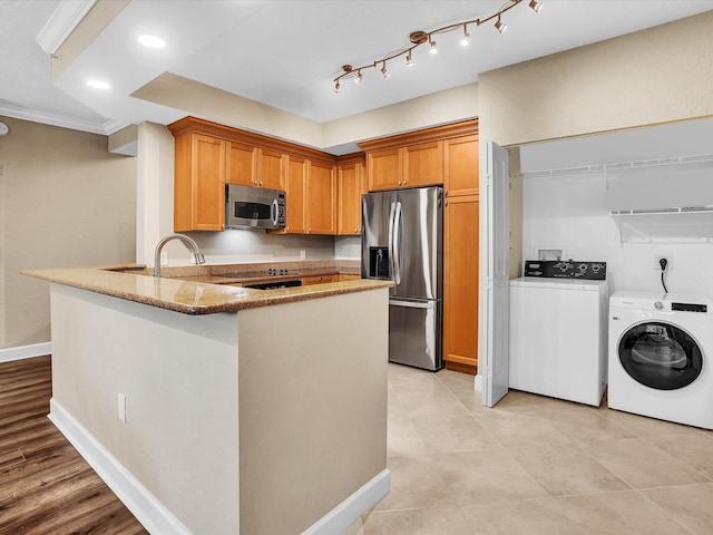 2 Renaissance Way Unit 302, Boynton Beach, FL 33426 - kitchen with appliances with stainless steel finishes, separate washer and dryer, light stone counters, a peninsula, and ornamental molding