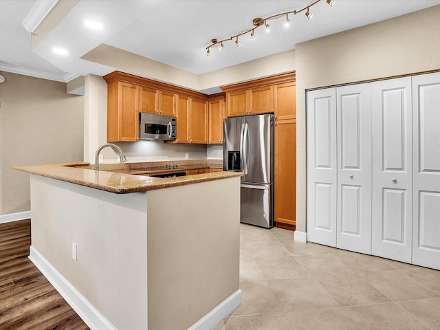 2 Renaissance Way Unit 302, Boynton Beach, FL 33426 - kitchen featuring stainless steel appliances, light stone countertops, a peninsula, ornamental molding, and brown cabinets
